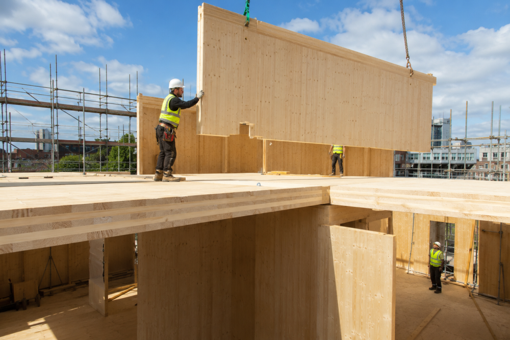 Cross-laminated timber panel lifted by crane on a mid-rise construction site